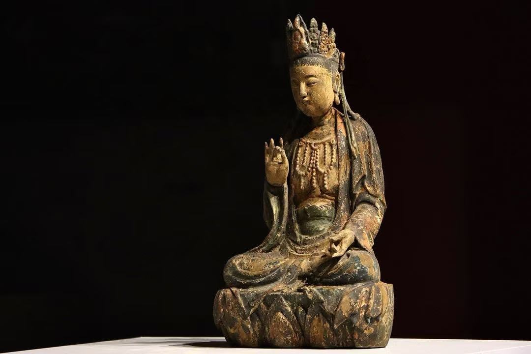 A SITTING STATUE OF GUANYIN CARVED FROM WOOD FROM THE MING DYNASTY: H:42cmThis is a seated painted wooden statue of Guanyin Bodhisattva, wearing an ornate crown and beaded necklace, seated in half-lotus posture on a lotus throne, with the right hand forming Abhaya Mud