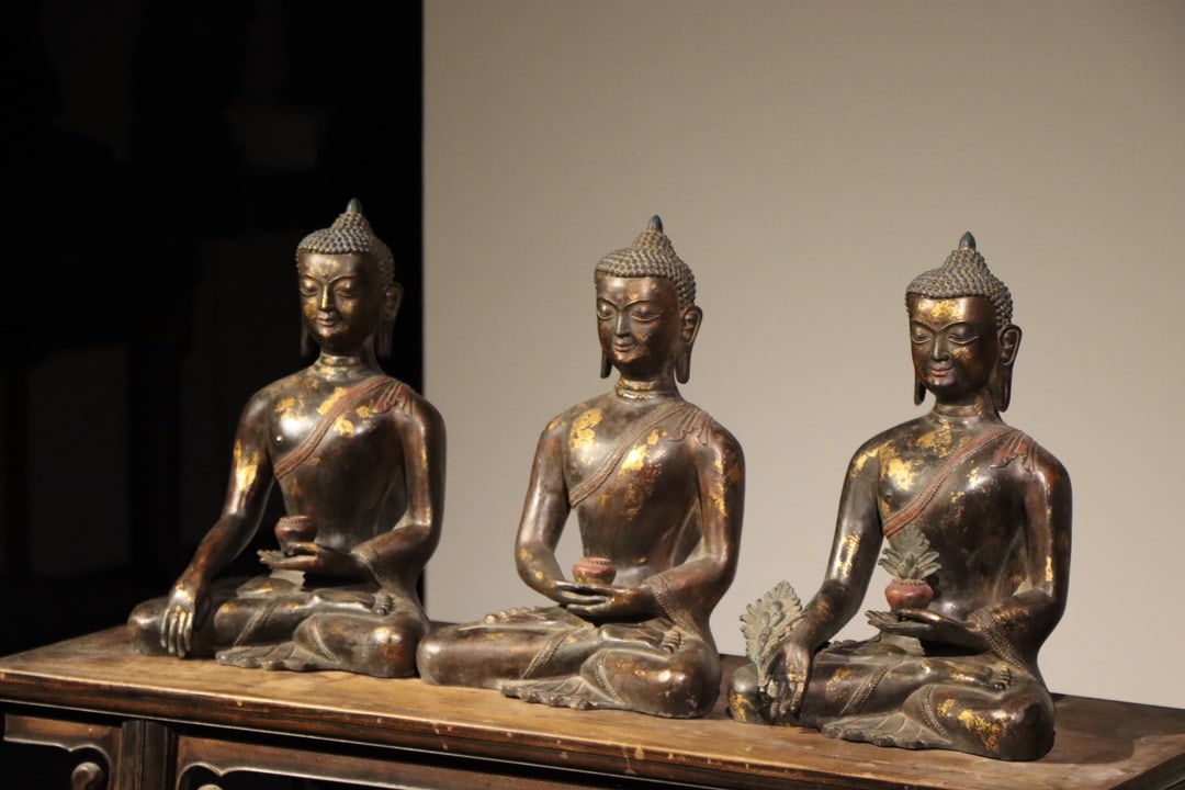 QING DYNASTY GILDED BRONZE STATUE OF THE THREE BUDDHAS SITTING (: H:40cm(15.75in)W:28cm(11.02in)T:18cm(7.09in)From left to right, they are respectively Dipankara Buddha (Past Buddha), Sakyamuni Buddha (Present Buddha) and Medicine Buddha (Future Buddha). Each statue