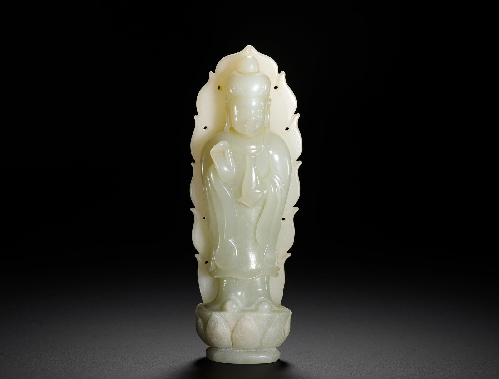 SEATED STATUE OF GUANYIN IN A PURE VASE MADE OF HETIAN JADE FROM THE QING DYNASTY: Height:13cm(5.12in) Width:5cm(1.97in) Weight:200g(0.44lb)Qing Dynasty Hetian white jade seated Guanyin statue with hollowed flame halo. The Bodhisattva sits lotus posture holding pure vase with preach
