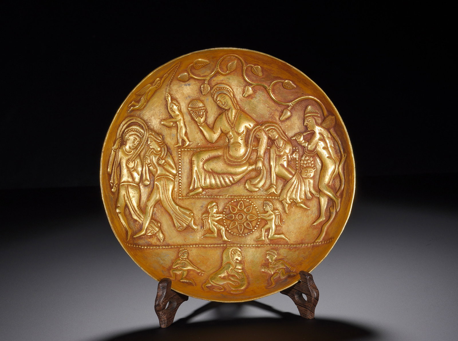 A Han Dynasty silver-gilt disc with patterns of figures and stories: Height:3cm(1.18in), Diameter:20.5cm(8.07in), Weight:610g (1.345lb)The work demonstrates masterful techniques of repoussé and chasing. The narrative composition is coherent with vivid dynamic figures.