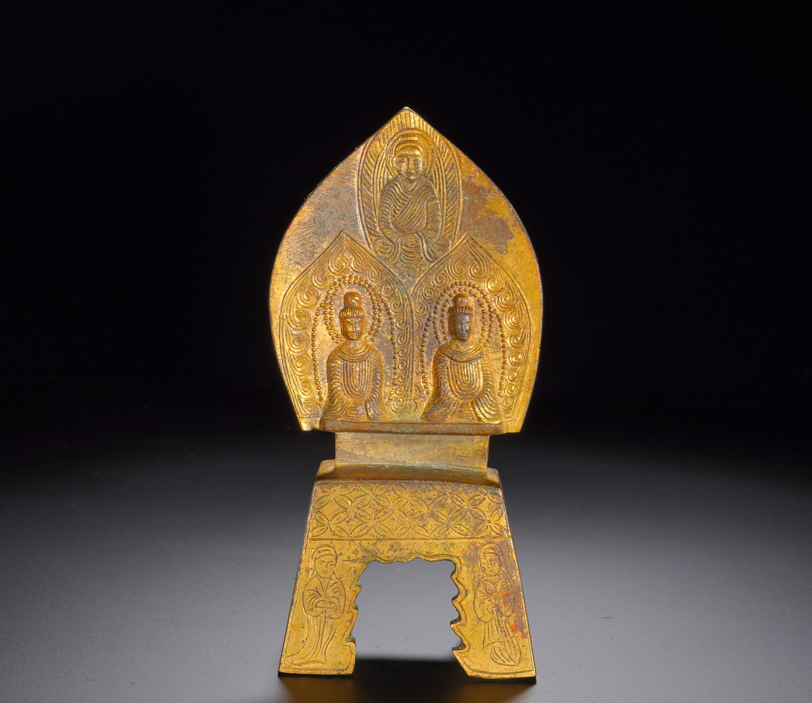 Three Buddha statues in gilded bronze of the Northern Wei Dynasty, from the fourth year of Taihe: Height:19.5cm(7.68in), Width:9cm(3.54in), Weight:780g (1.720lb)This gilt bronze Northern Wei votive figure belongs to the well-known “bench-style Buddha” type. It features a peach-shaped mando