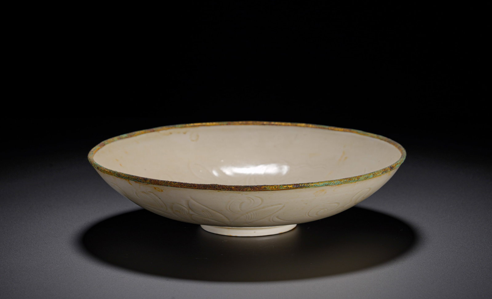 A white glazed shallow-bellied bowl from Ding kiln of the Song Dynasty: Height:4.5cmWidth:20.5cmWeight:340gWide mouth, shallow curved belly, short circular foot, thin and elegant body, a classic Song Dynasty Ding ware shape. The mouth rim is unglazed, mounted with gilded