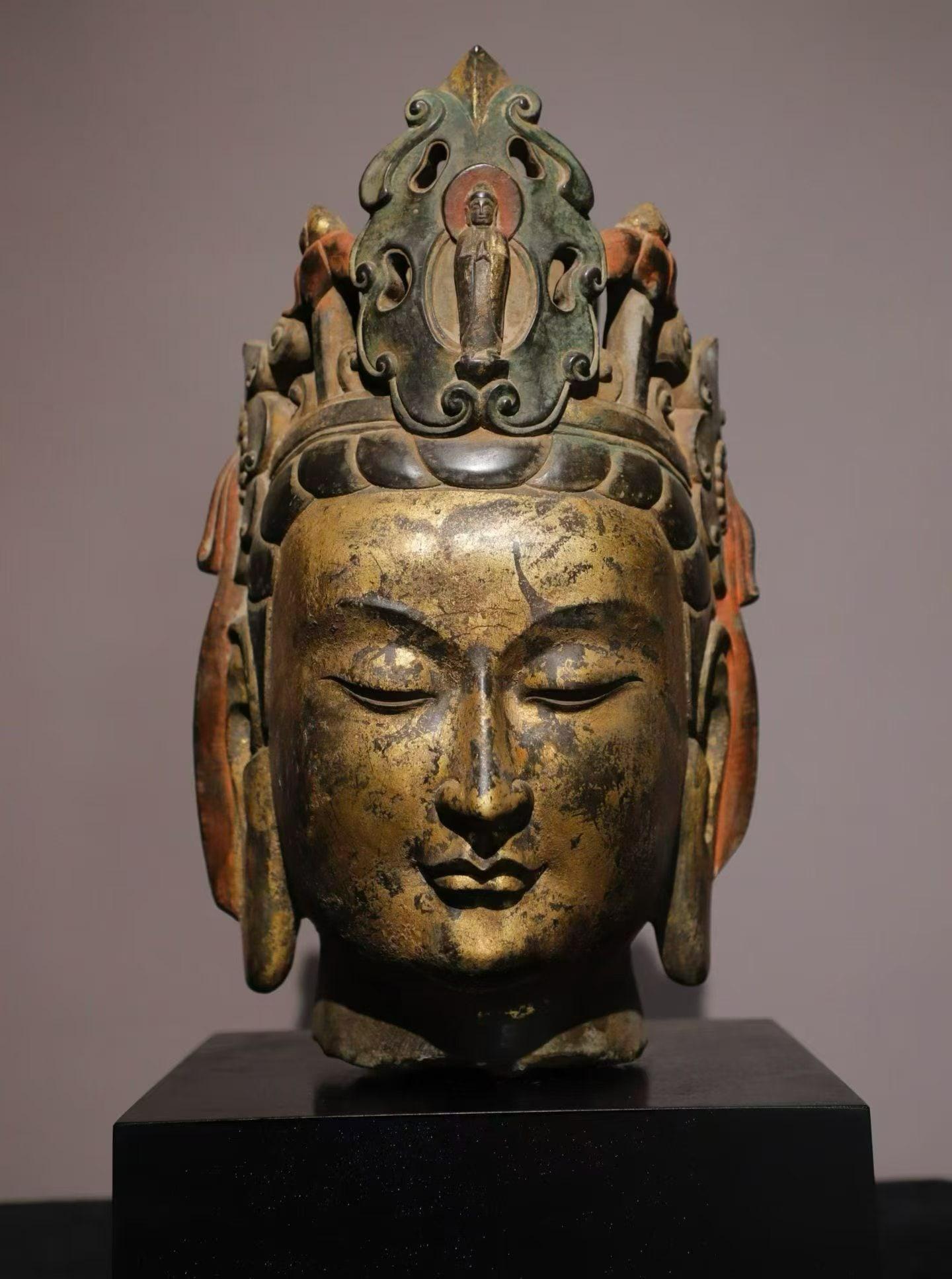 Northern Qi stone-carved gilded painted head of Guanyin Bodhisattva: Height:36cm(14.17in)Stone Guanyin Bodhisattva head with gilding and polychrome, mounted on modern base. The facial features are elegant and serene with half-closed eyes. The openwork crown is decorate