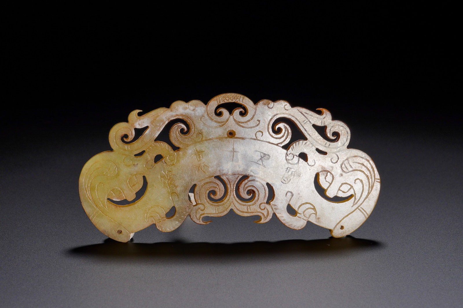 Qin Dynasty engraved double Dragon Jade pendant: Height:4.5cm(1.77in) Width:9.5cm(3.74in) Weight:20g(0.04lb)Arcuate jade pendant shaped as half-disc. Dragon heads at terminals, openwork scroll ornament, inscribed auspicious text. Huang was essential
