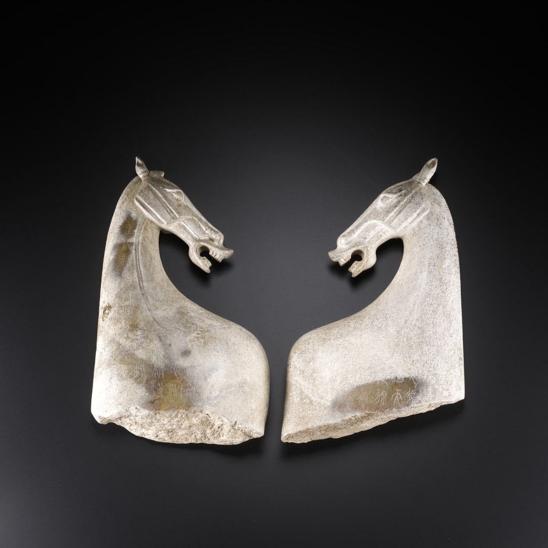 A pair of Han Dynasty Hetian jade poetic horse heads: Long:9cm(3.54in), Width:3.8cm(1.50in), Height:14cm(5.51in), Weight:953g (2.101lb)Pair of inscribed ancient jade horse heads. The jade is covered with aged white patina. The horses are sculpted with ra