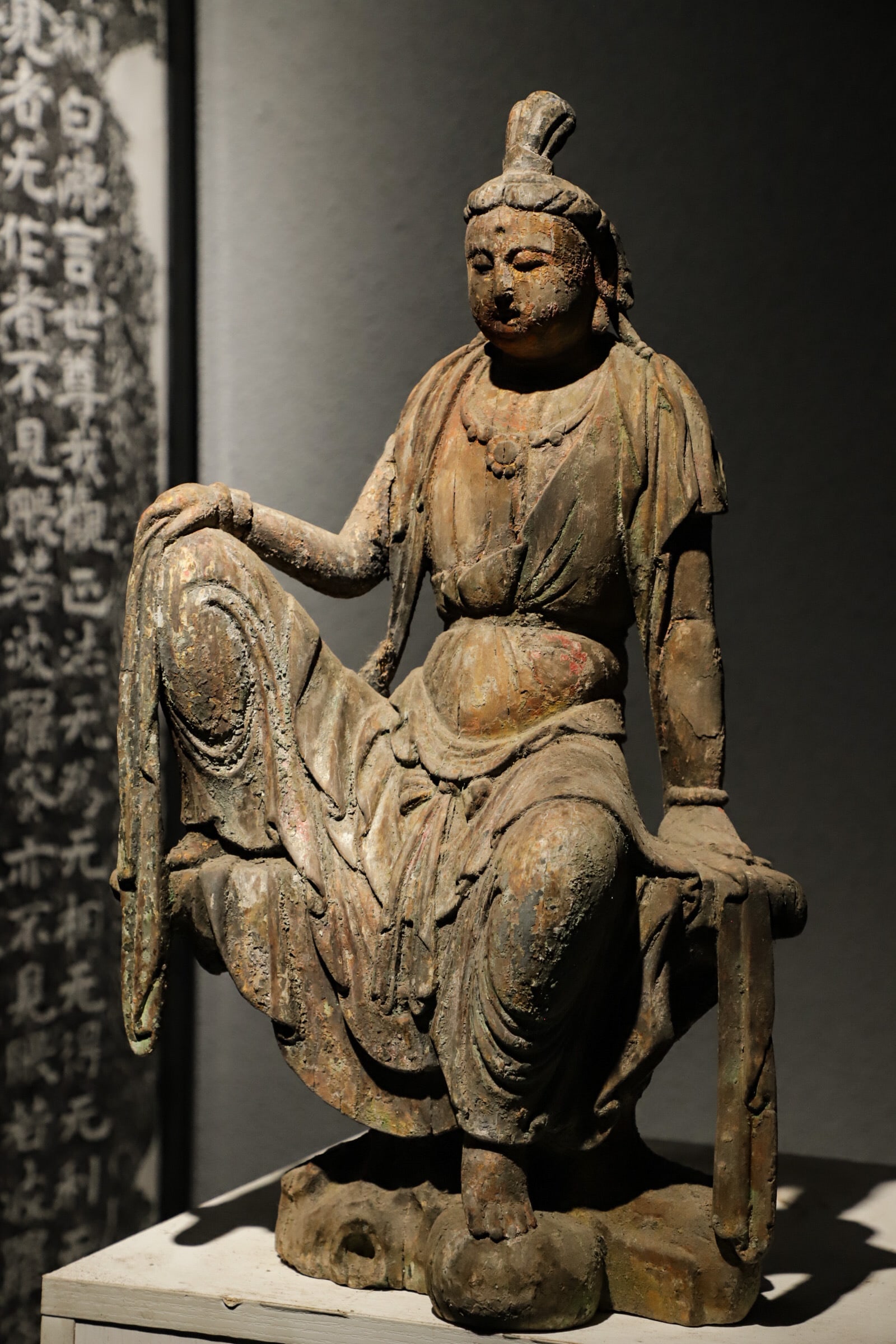 A Song Dynasty woodcarving statue of the Free and Easy Guanyin: Height:52cm(20.47in), Long:30cm(11.81in), Width:18cm(7.09in)The wooden Guanyin wears a high bun, with gentle and tranquil facial features. Adorned with neck ornaments, layered robes flow naturally. Pr