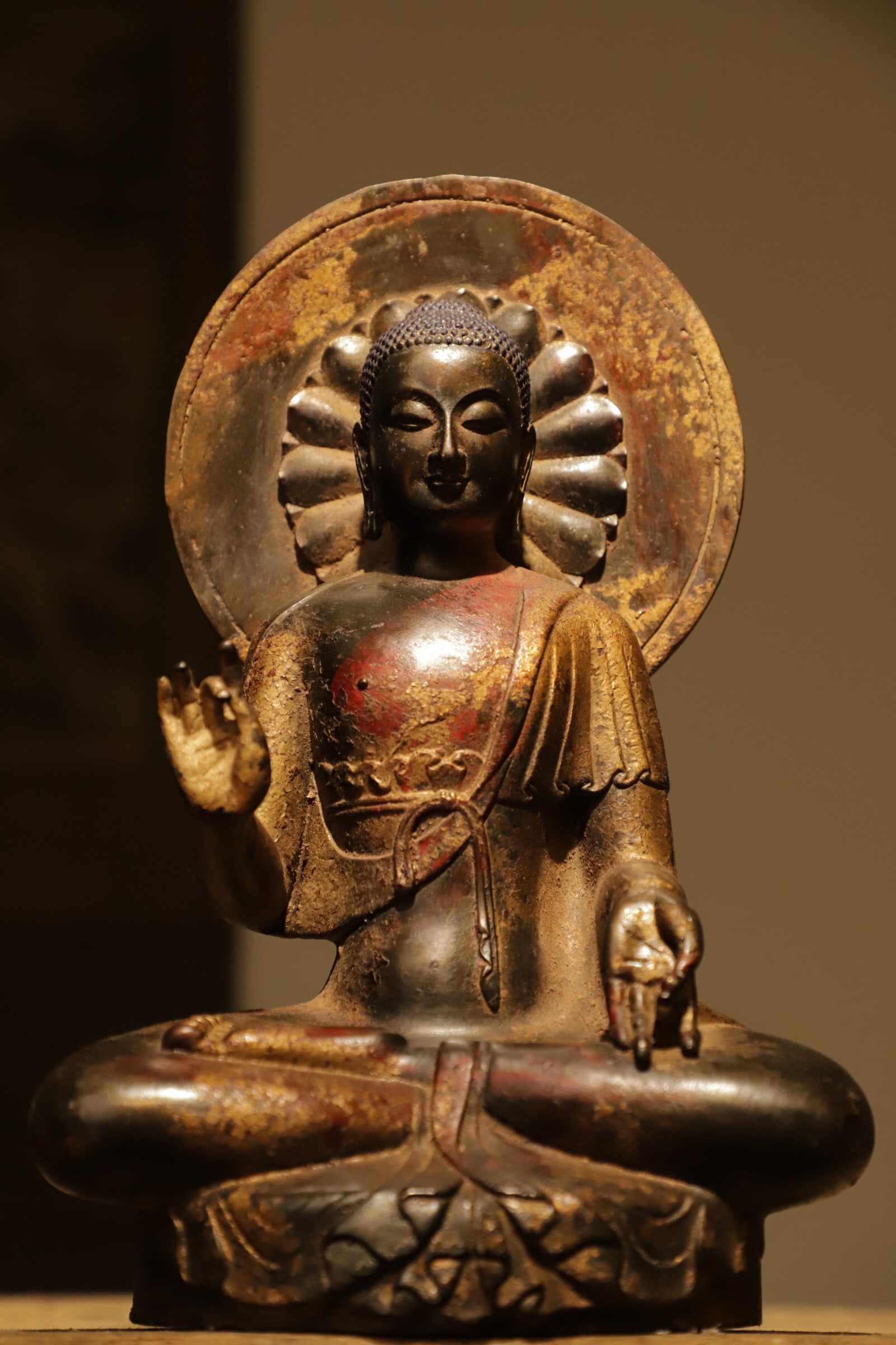 A gilded bronze backlit statue of Sakyamuni from the Ming Dynasty: Weight:2727g (6.012lb), Height:28cm(10.63in), Long:18cm(7.09in), Width:12cm(4.72in)Shakyamuni sits in full lotus posture on a lotus base. With serene facial features and lowered eyes, he wears a parti