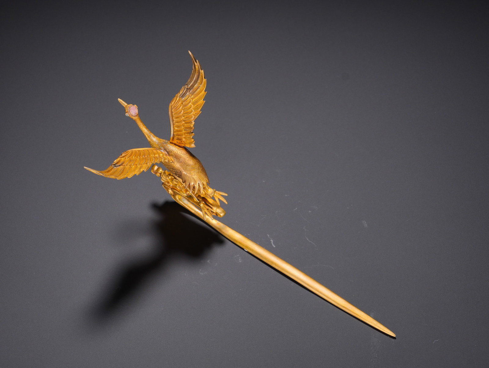 Gilded bronze hairpin with inlaid tourmaline and crane pattern from the Qing Dynasty: Long:21.5cm(8.46in), Width:12cm(4.72in), Weight:52g (0.115lb)Gold Hairpin with Chiseled Crane and Cloud MotifsForged entirely of gold, the head is modelled as a three-dimensional spreading-wing