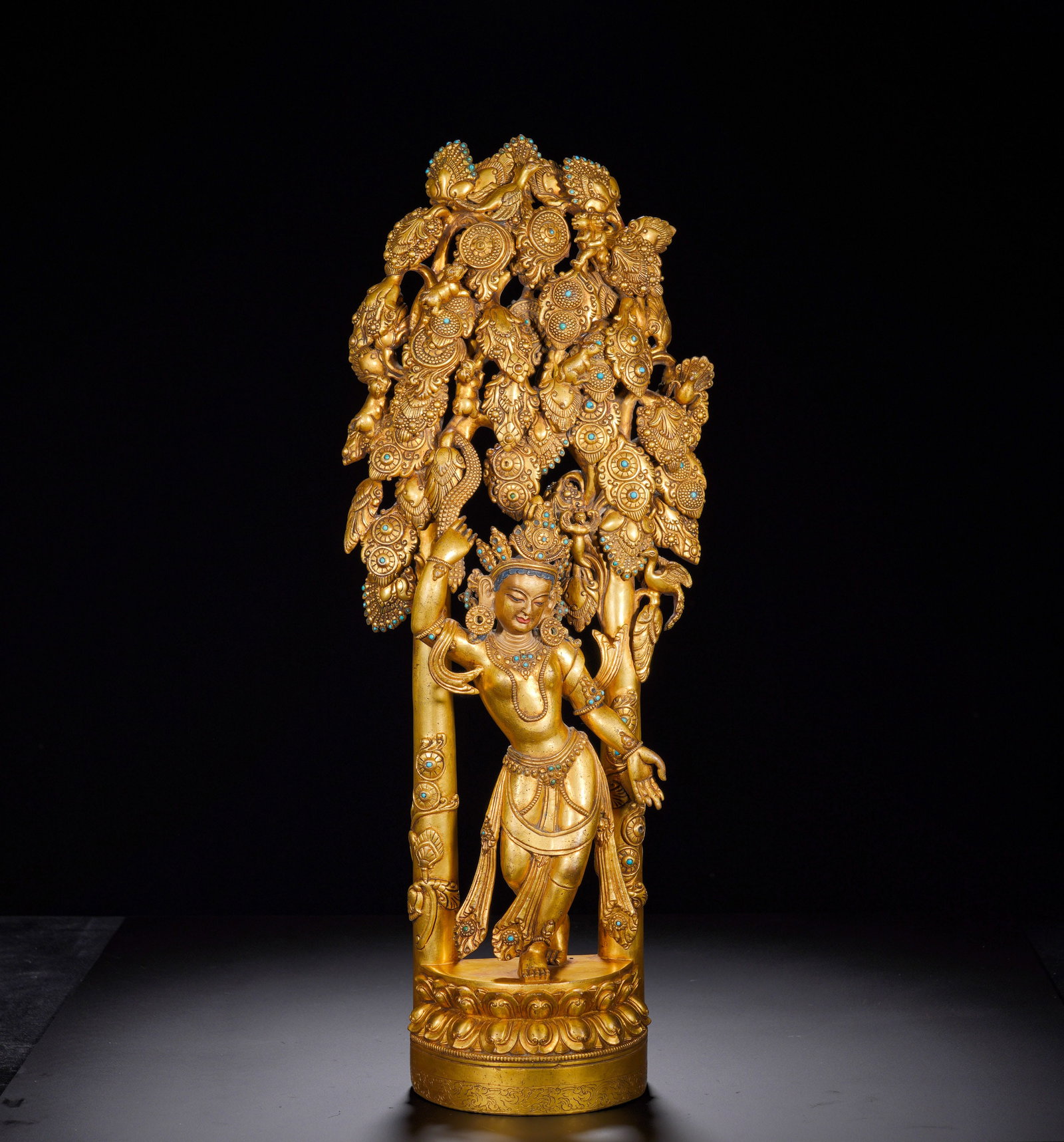 An 18th-century gilded bronze statue of Lady Maya: Height:52cm(20.47in), Width:14cm(5.51in), Weight:6620g (14.594lb)Gilt Bronze Standing Tara beneath the Bodhi TreeThis gilt bronze Tara stands gracefully in tribhanga pose upon a lotus base. She has a 