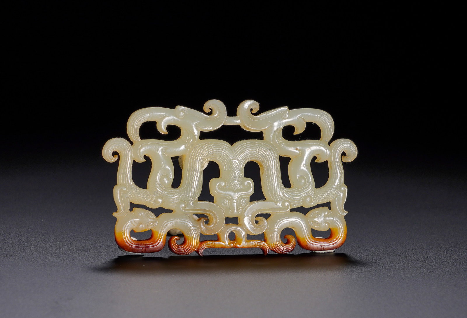 Qin Dynasty Hetian jade Dragon and Phoenix Pendant: Height:4.2cm(1.65in) Width:6.9cm(2.72in) Weight:20g(0.04lb)White jade ornament with hollow carving. Central beast mask, flanked by paired dragons and phoenixes. Dragon-phoenix motif stands for harmoni