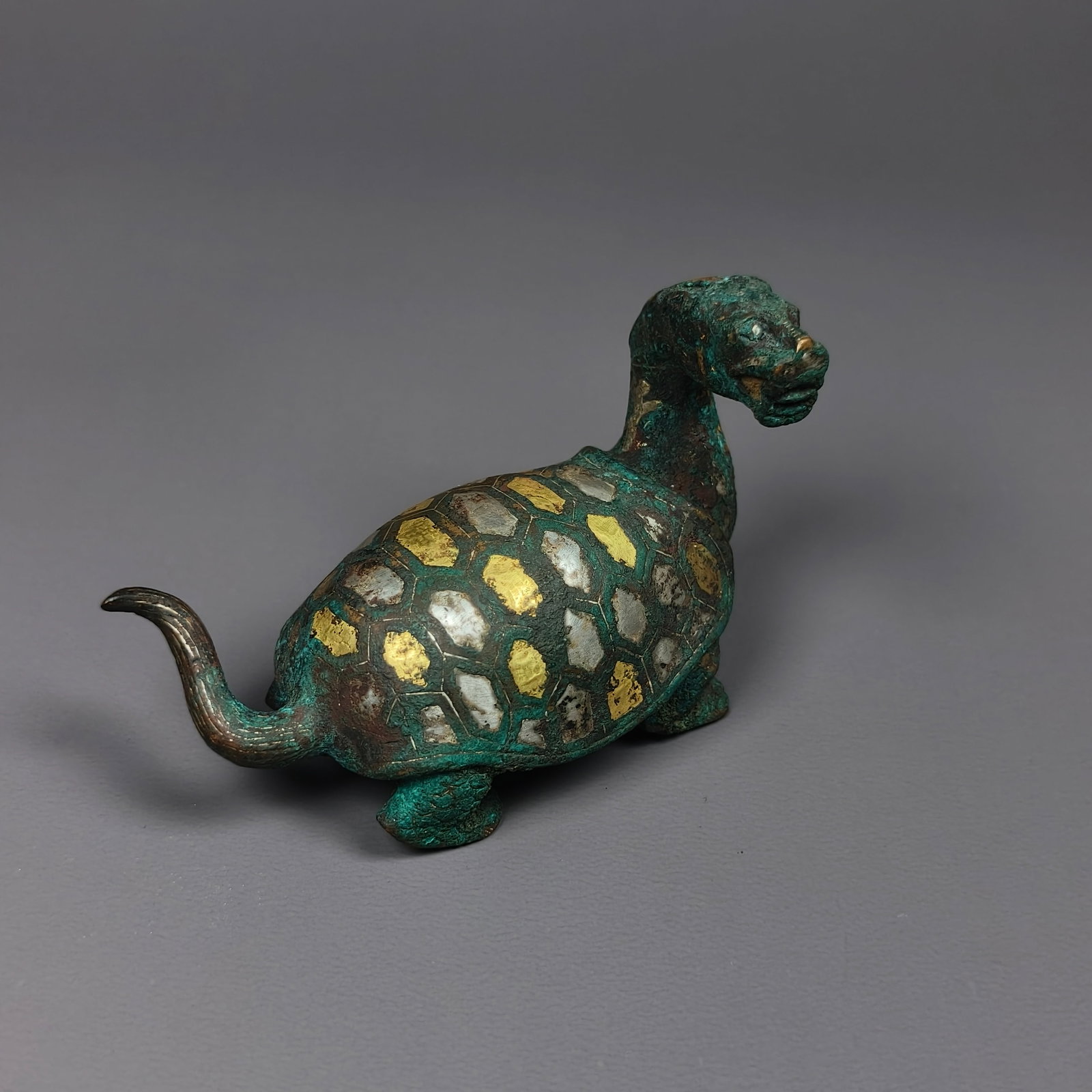 A copper town of inlaid gold and silver from the Warring States period: Height:6cm(2.36in), Width:8cm(3.15in), Weight:154g (0.340lb)Warring States Bronze Turtle-Dragon Paper Weight with Gold & Silver InlayBronze basalt spirit sculpture with turtle body and dragon head. Th