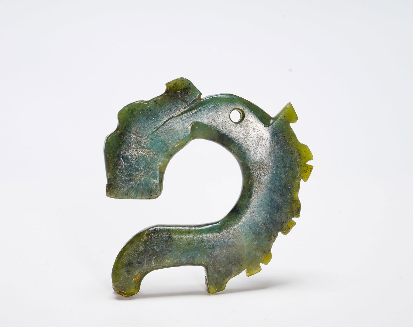 Red Mountain period Jade C-shaped dragon pendant: Height:9.5cm(3.74in) Width:9.5cm(3.74in) Weight:110g(0.24lb)The jade ornament takes classic open C-form. Carved green jade with simple dragon head, serrated flanges along outer edge, perforation on