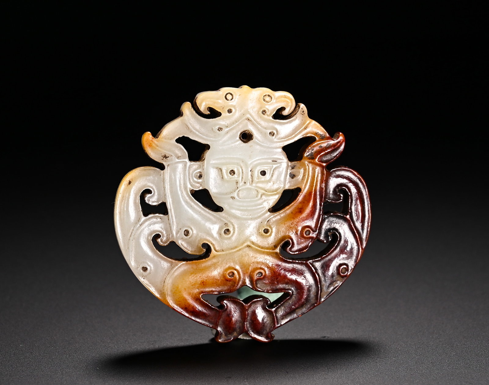Han Dynasty Hetian jade red through-carved Divine Figure Double Dragon Pendant: Height:5.6cm(2.20in)Width:5.5cm(2.17in)Weight:40g(0.09lb)Han Dynasty Hetian jade openwork pendant carved with deity and twin dragons. Centered on a frontal divine human figure flanked by confronting