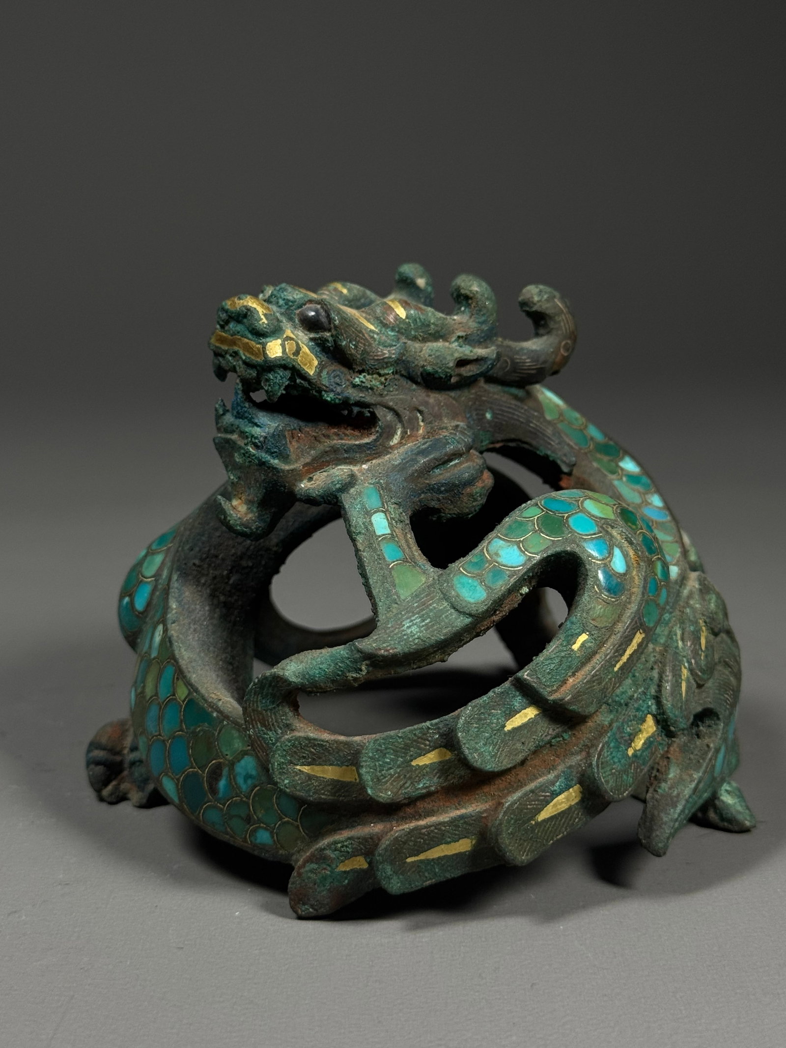 Bronze town with gold inlaid and turquoise coiled dragon from the Warring States period: Height:8cm(3.15in), Width:9cm(3.54in), Weight:711g (1.567lb)Warring States Coiled Dragon Bronze Weight Inlaid with Gold & TurquoiseCast in bronze, this mat weight takes the form of a hollow interwoven