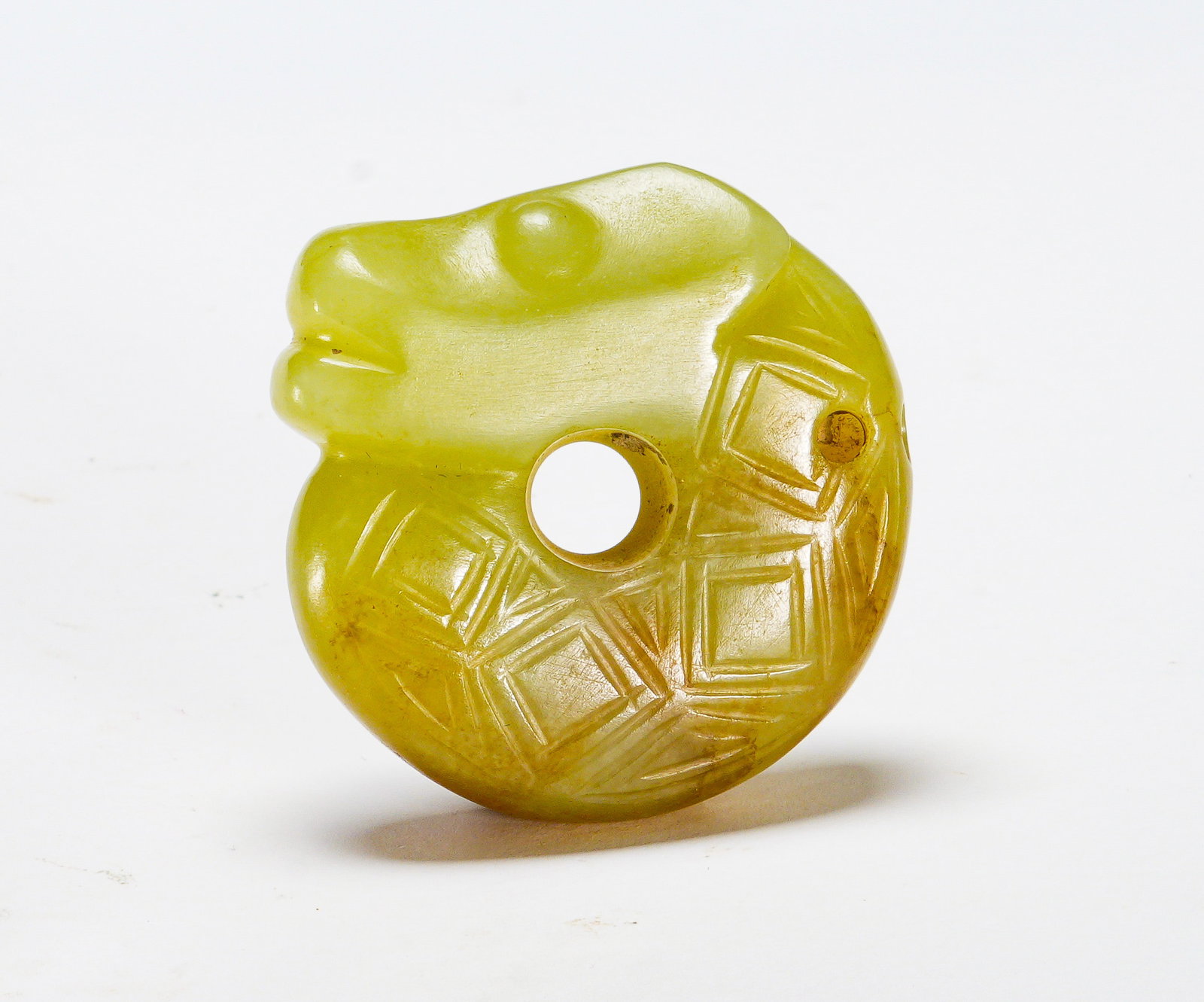 Red Mountain period C-shaped dragon pattern jade pendant: Height:4cm(1.57in) Width:4cm(1.57in) Weight:40g(0.09lb)The yellowish jade ornament with central hole, carved dragon head, interlaced square lattice patterns, suspension perforation. Disc symbolizes he