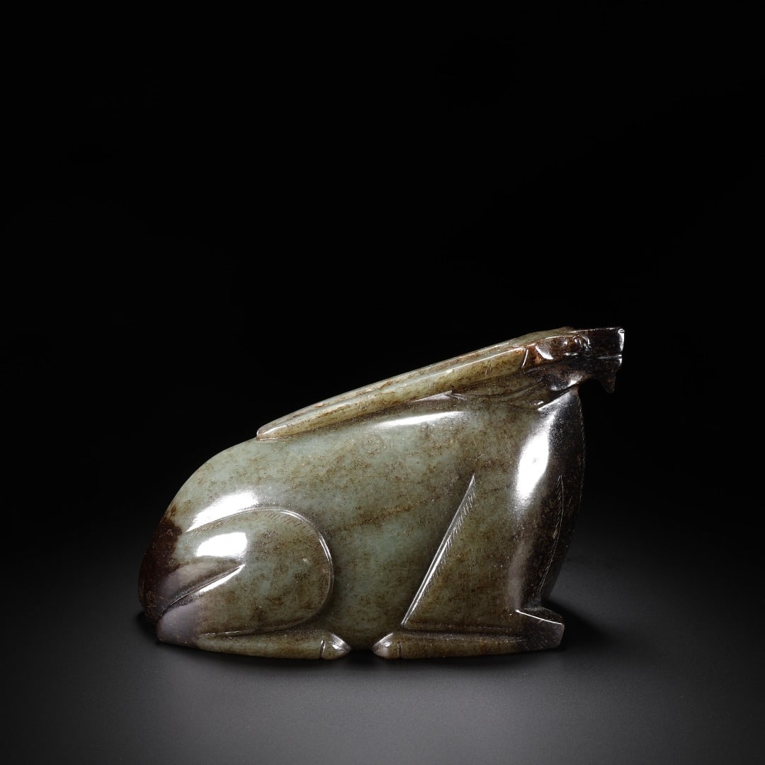 Han Hetian jade rabbit figurine: Long:15cm(5.91in), Width:6.7cm(2.64in), Height:9.1cm(3.58in), Weight:1199g (2.643lb)Carved from celadon jade with mild texture and natural dark brown ancient patina. The rabbit lies in a resting postu