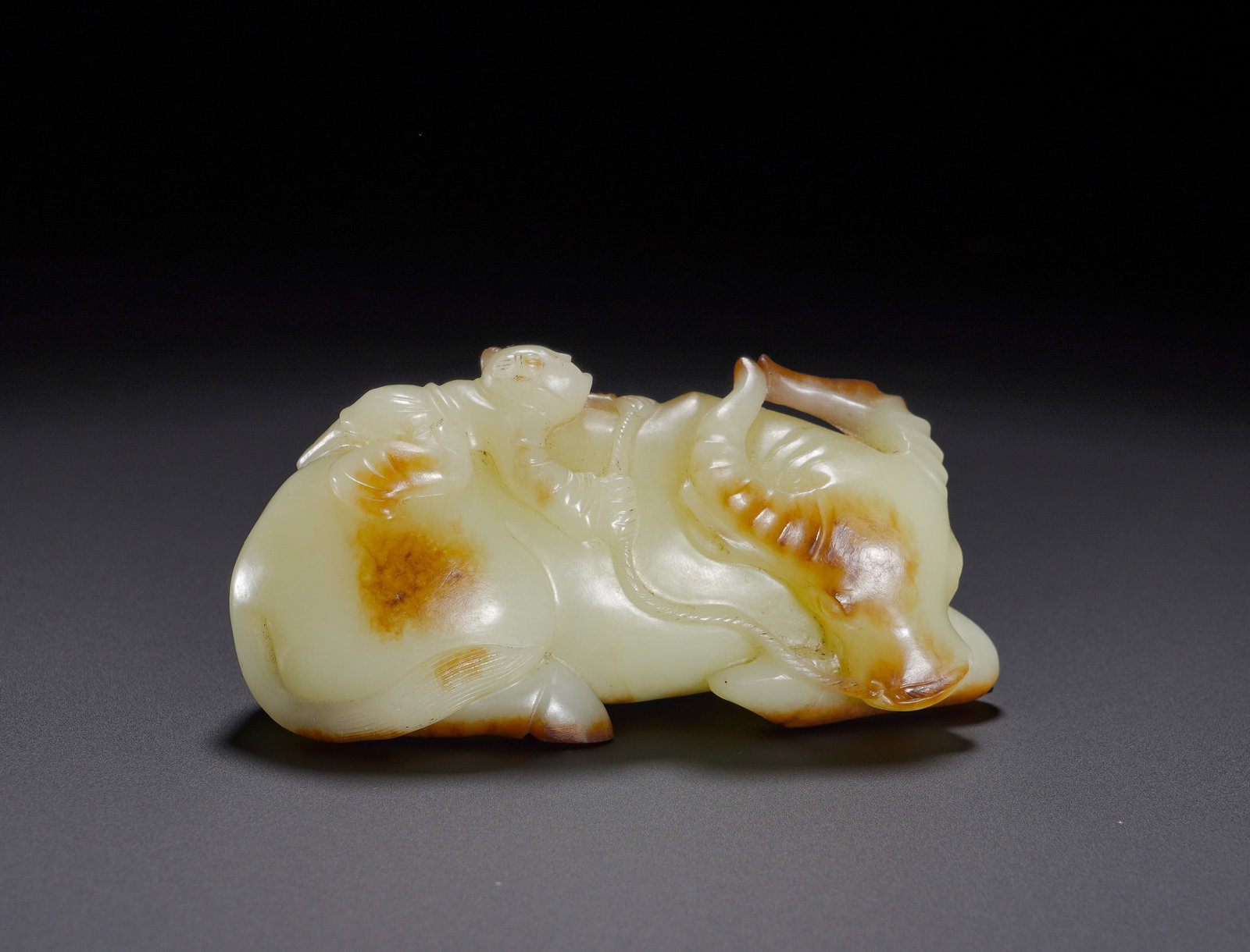 Hetian white jade from the Qing Dynasty shows a boy with a skin herding a cow: Height:4.4cm(1.73in), Width:9cm(3.54in), Weight:200g (0.441lb)White Hetian Jade Ornament: Boy Herding Buffalo with Natural Russet SkinCarved from fine white Hetian jade with lustrous, oily texture, th