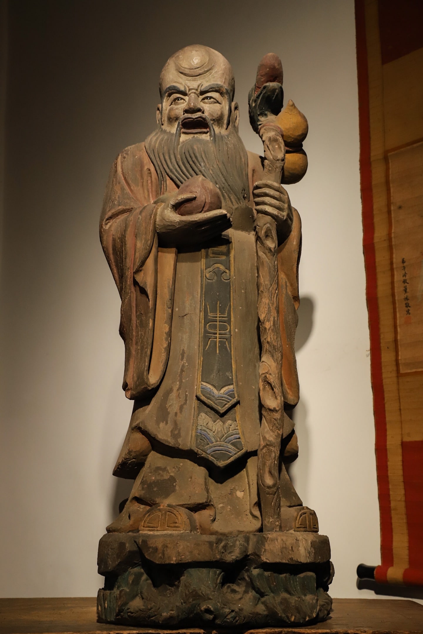 Painted wood carvings of the Longevity star in the Ming Dynasty: Height:104cm(40.94in), Long:40cm(15.75in), Width:32cm(12.60in)This polychrome wood standing statue of the God of Longevity dates to the Ming Dynasty. Made of wood with painted pigments, its colored la