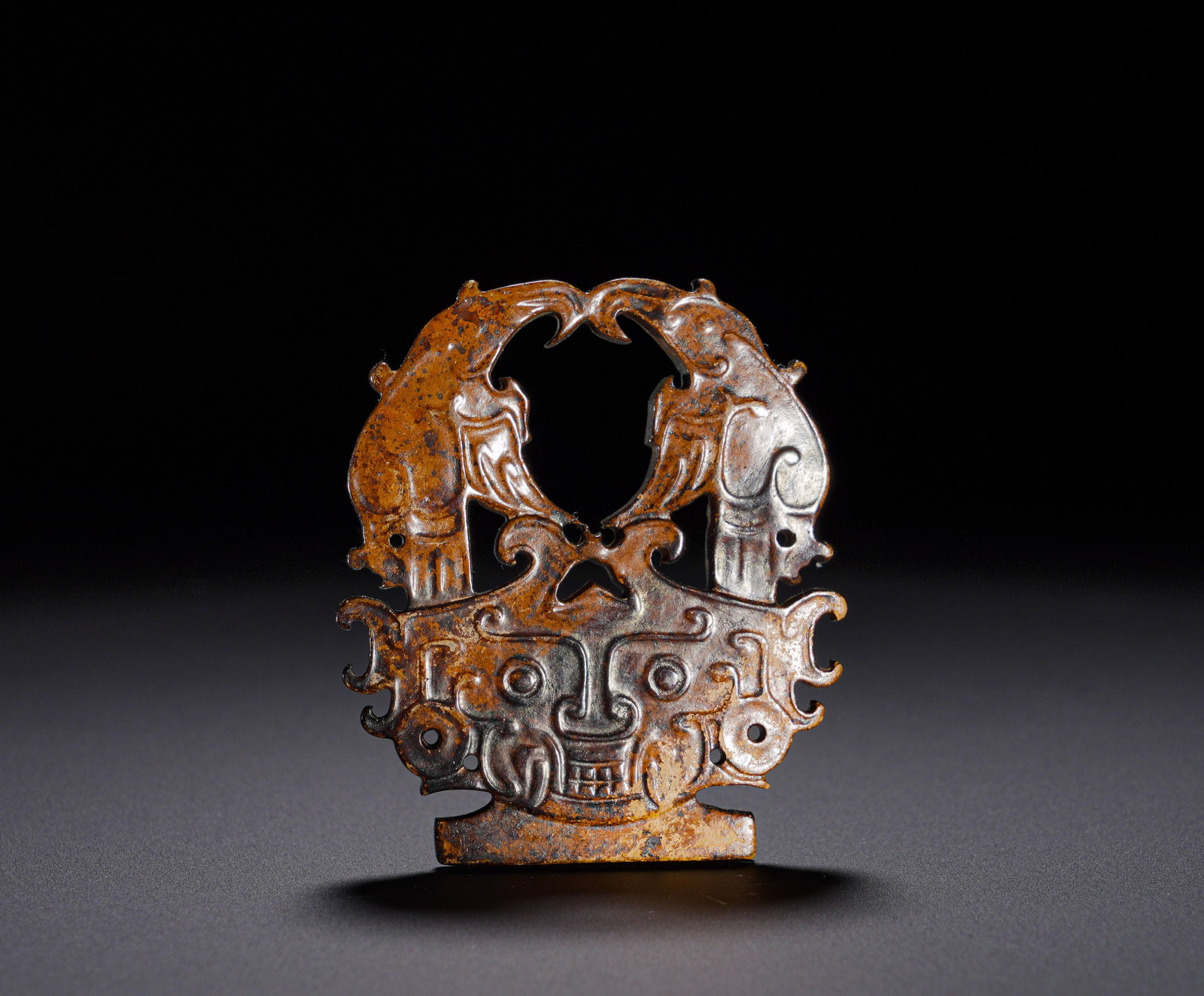 Shang Dynasty through-carved Double Dragon Taotie jade pendant: Height:5.8cm(2.28in), Width:4.8cm(1.89in), Weight:30g (0.066lb)Archaic Jade Openwork Pendant with Twin Phoenixes and Beast MaskThe jade is covered in deep aged brown patina with thick antique surface