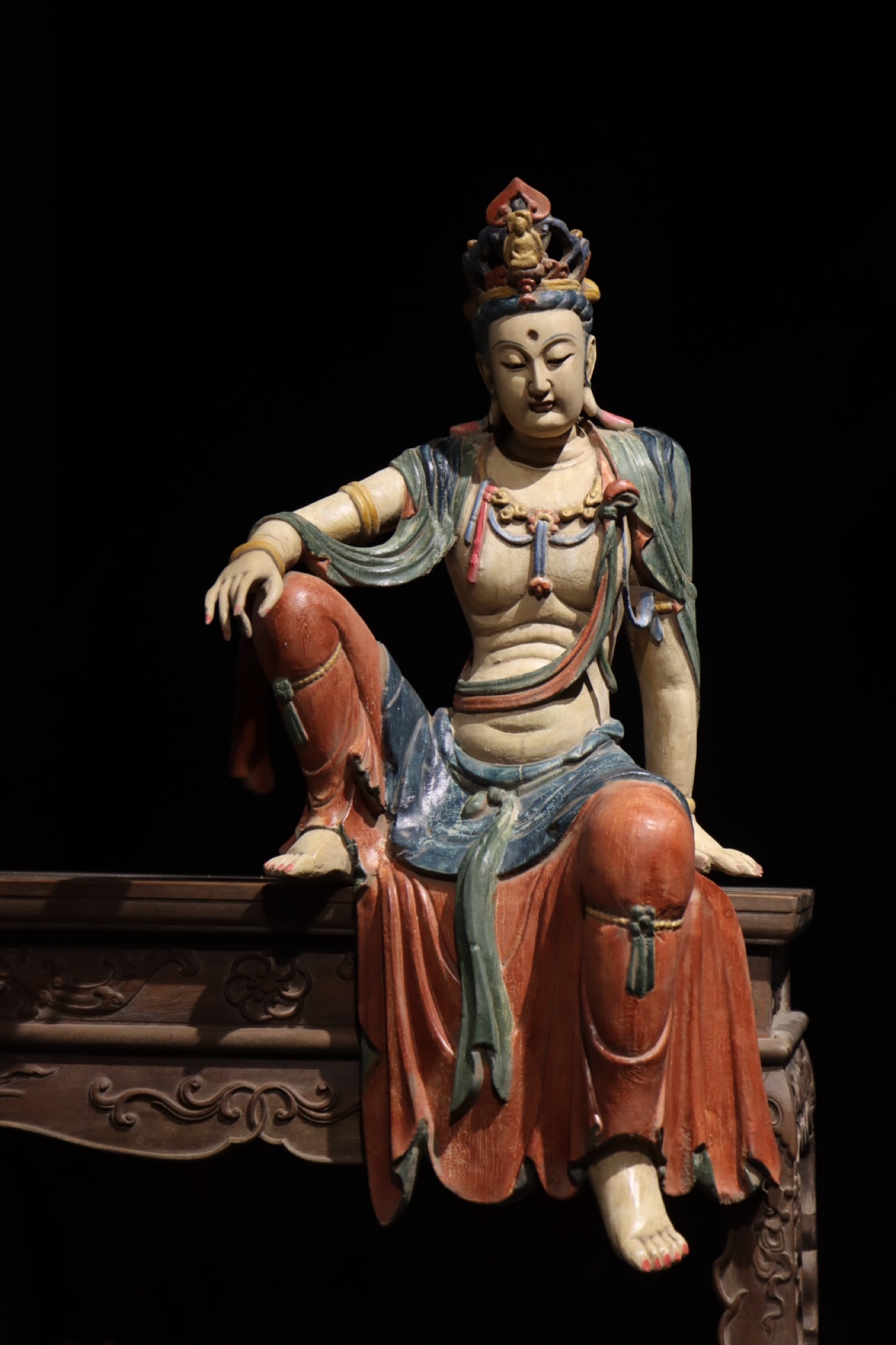Liao Dynasty woodcarving of the Free and Easy Guanyin: Height:62cm (24.41in)Wooden polychrome Guanyin Bodhisattva in relaxed sitting posture, small Buddha carved on crown, layered pearl necklaces, draped robes painted with traditional mineral colors,