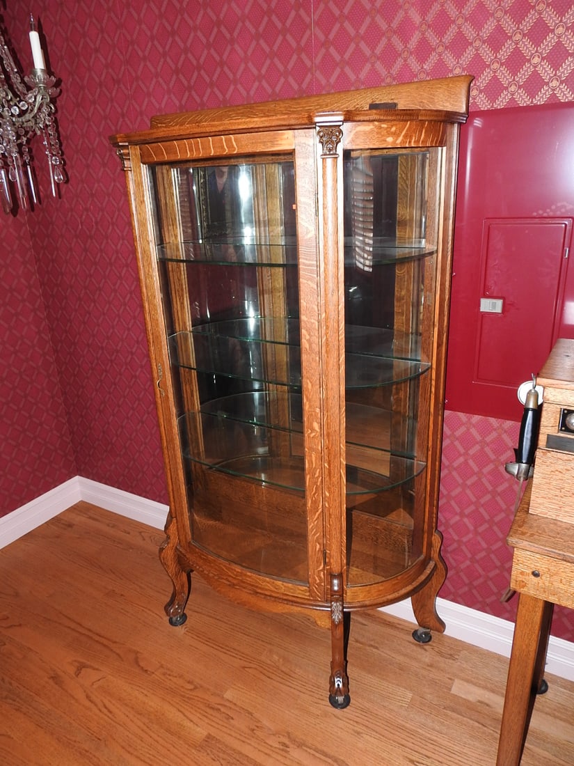 Oak Curved Glass Lighted Curio Cabinet: Vintage oak curved-glass curio display cabinet with glass shelves and later-added lights. Contents shown in photos are not included. Approx. 66 x 40 x 13 in. Shows age-related wear, patina, finish