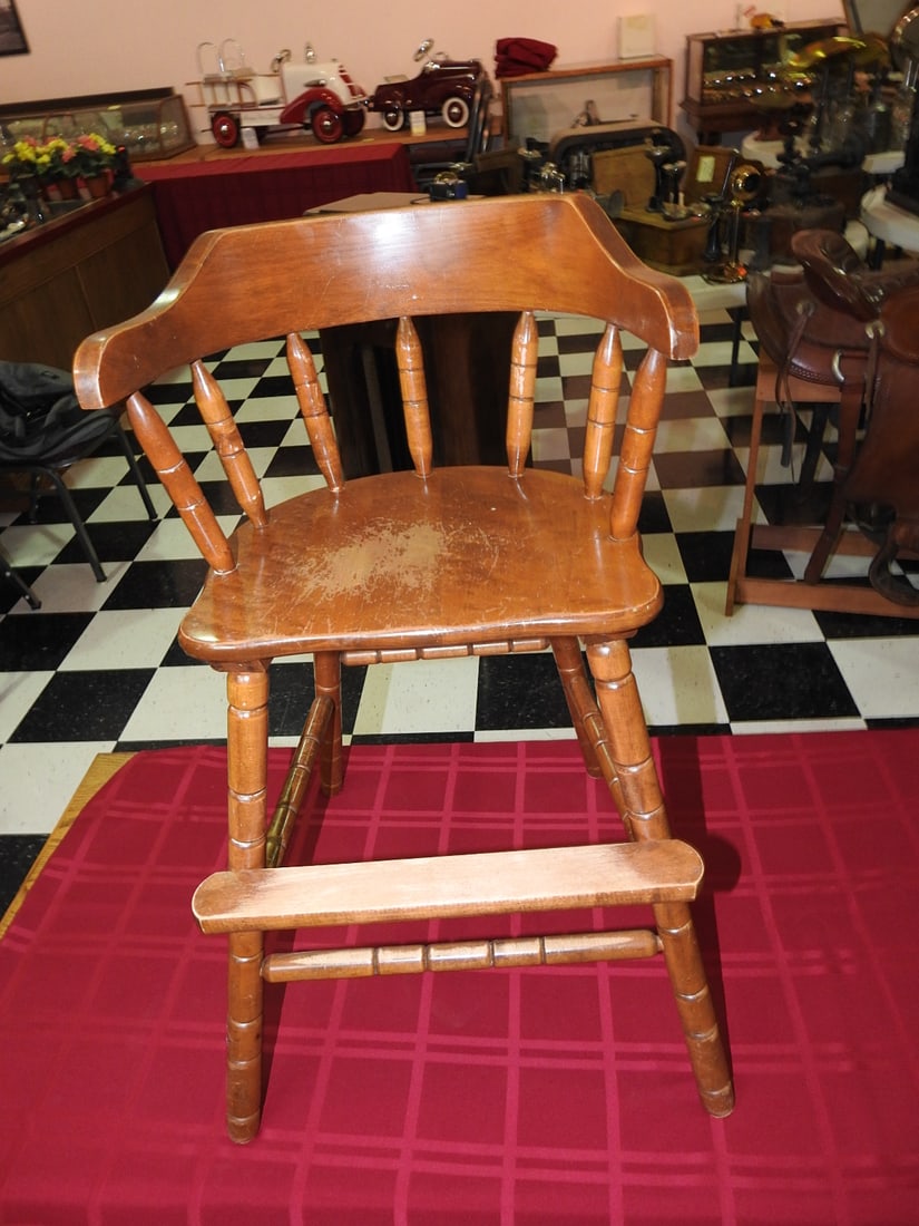 1920s Wooden Child High Chair: Antique 1920s wooden child high chair with spindle back, arms and footrest. Approx. 30 x 16 x 19.5 in. Shows finish wear, scratches, scuffs, age toning and handling wear consistent with age and use.