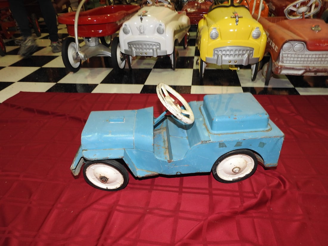 Vintage Blue Ride-On Jeep Toy: Vintage blue ride-on Jeep-style toy with white steering wheel and metal body. Approx. 13 x 10.5 x 26 in. Maker not clearly visible. Shows paint wear, scratches, oxidation, wheel wear and age-related u