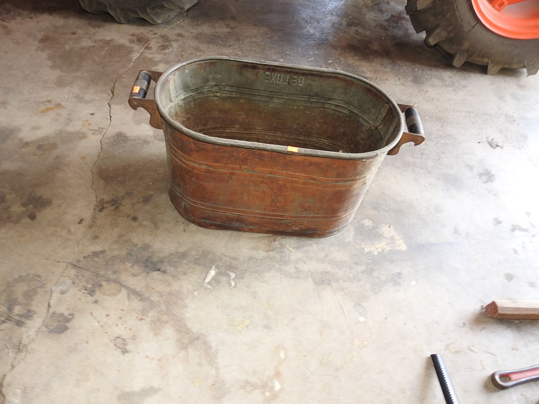 Vintage Deluxe Copper Wash Tub: Vintage oval copper/metal wash tub marked Deluxe with side handles. Shows tarnish, verdigris, dents, oxidation, patina, and age-related use wear. Approx. 13 x 28 x 13 in.