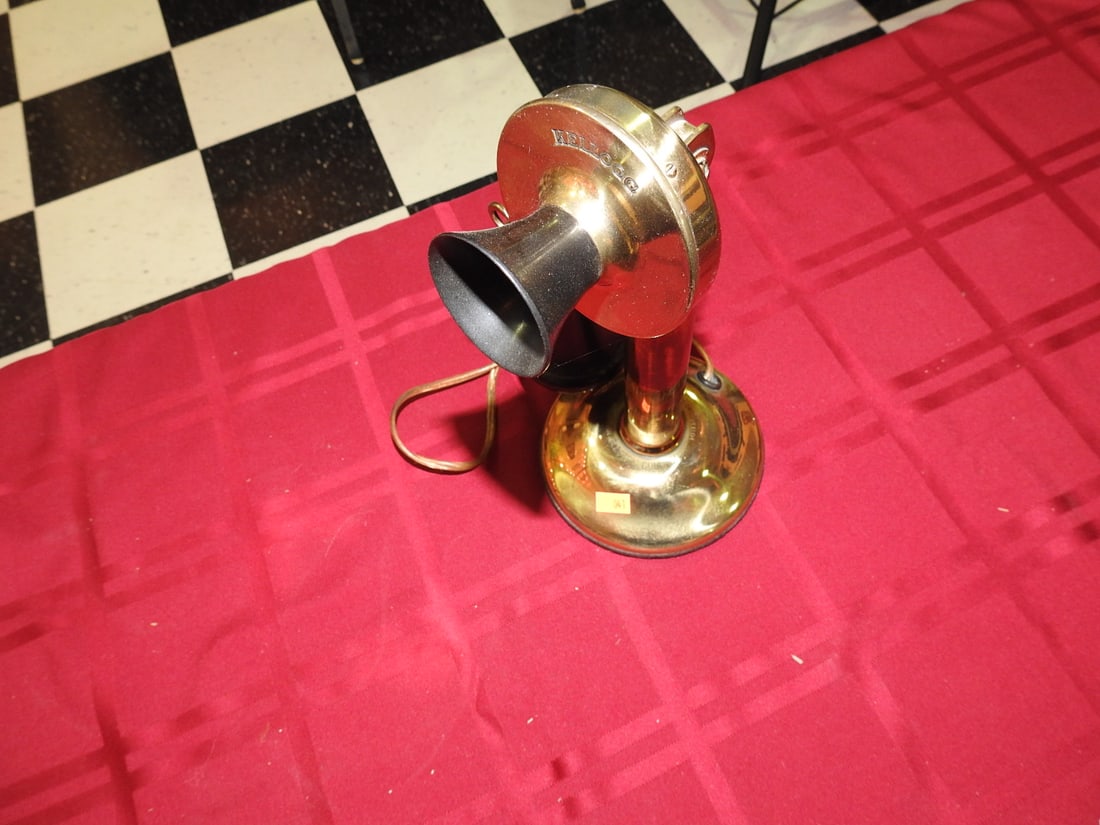 Kellogg Brass Candlestick Telephone: Antique Kellogg candlestick telephone with brass/gold-tone base, upright stem, receiver, black mouthpiece, and cord. Kellogg marking visible on transmitter/mouthpiece area. Shows tarnish, patina, scuf