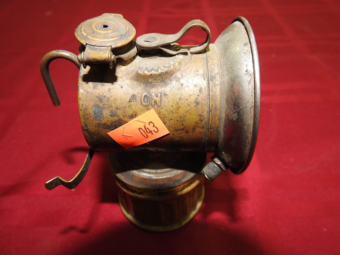 Justrite Brass Carbide Lamp: Antique Justrite brass carbide/miner-style lamp marked Trade Mark Justrite, Made in U.S.A., Pat. Applied For. Includes reflector, hook/handle hardware, and lower reservoir. Shows tarnish, oxidation, d