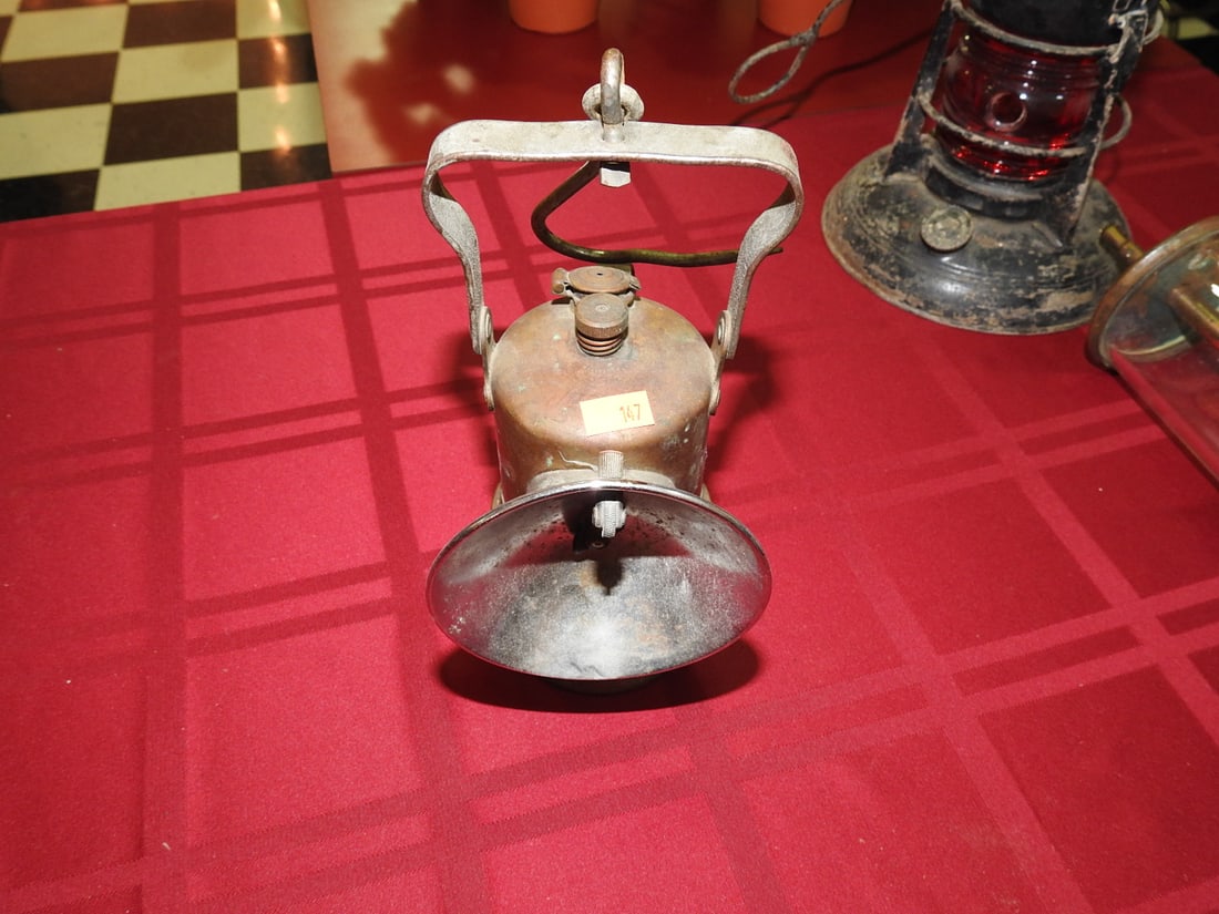 Justrite Miner Lamp: Vintage Justrite miner lamp with metal body, hook/handle and worn finish. Approx. 9 x 4 x 3 in. Lighting function not tested. Shows age-related wear, patina, finish wear, oxidation, surface scratches 