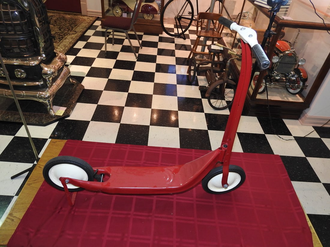 Restored Red Vintage Scooter: Restored vintage red scooter with white wheel accents and foot brake. Approx. 32.5 x 13 x 35 in. No badge or branding visible. Foot brake reported functional. Shows restoration/display wear, paint