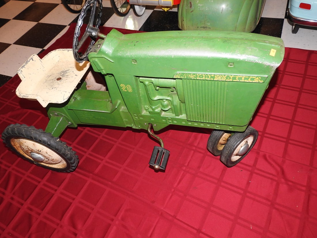 John Deere 20 Pedal Tractor: John Deere 20 pedal tractor with green and yellow styling, metal body, steering wheel, seat and pedal drive. Approx. 26 x 20 x 39 in. Shows age/use wear, paint loss, scratches, oxidation, tire wear an