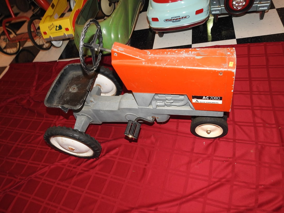 Allis-Chalmers AC-7020 Pedal Tractor, Broken Hitch: Allis-Chalmers AC-7020 pedal tractor with orange styling, metal body, steering wheel, seat and pedal drive; rear hitch is broken as pictured. Approx. 28 x 20 x 37 in. Shows age/use wear, paint loss,