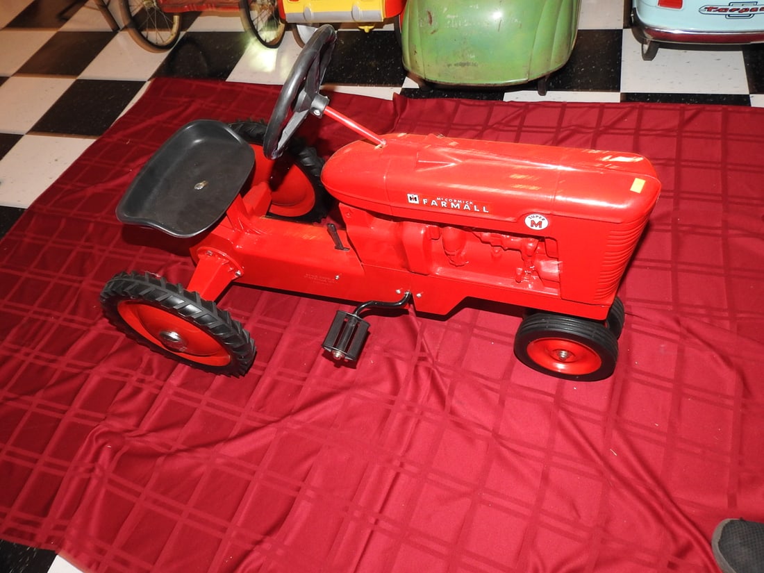 Reproduced McCormick Farmall Super M Pedal Tractor: International Harvester McCormick Farmall Super M pedal tractor with red styling, metal body, steering wheel, seat and pedal drive Reproduction. Approx. 26 x 20 x 37 in. Shows age/use wear, paint