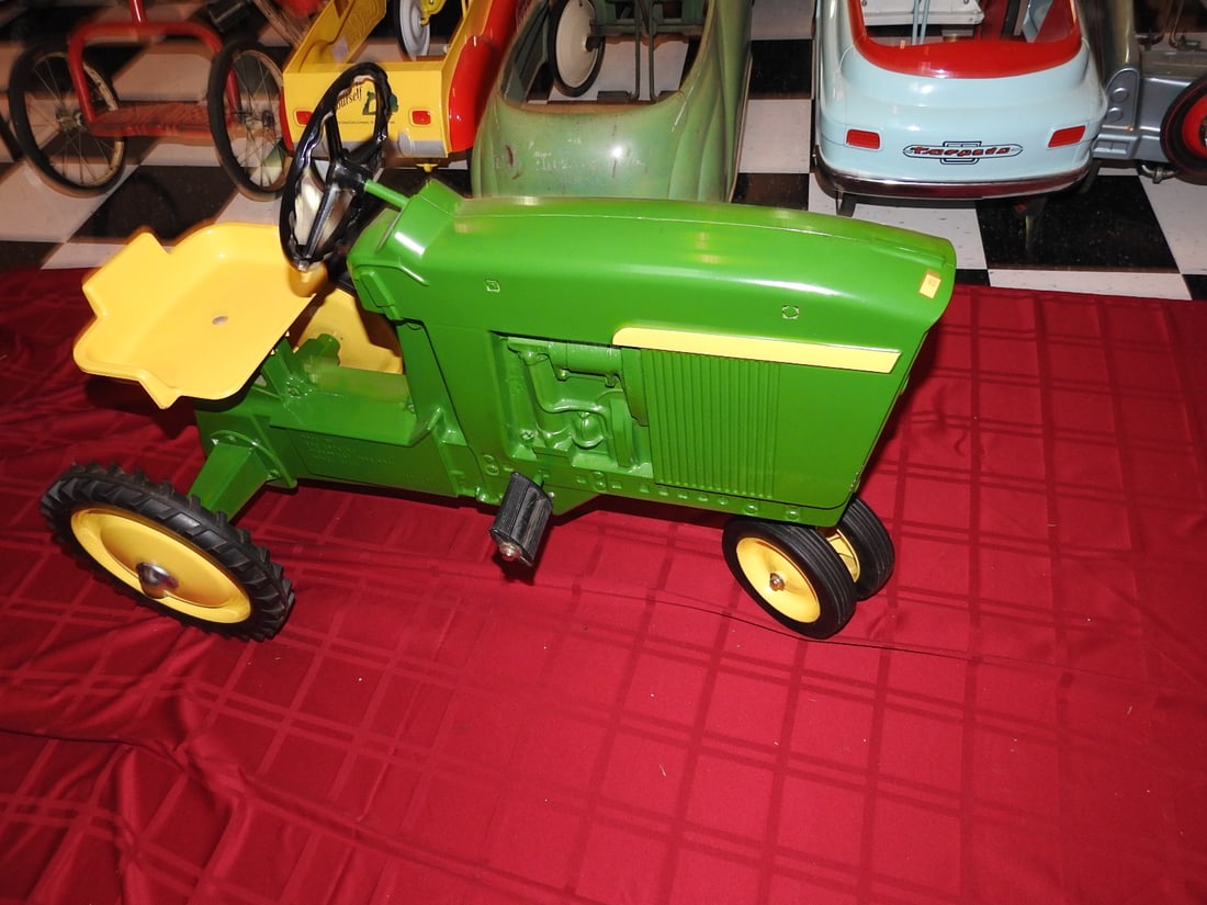 Restored John Deere Pedal Tractor: Restored John Deere pedal tractor with green and yellow styling, metal body, steering wheel, seat and pedal drive. Approx. 26 x 20 x 40 in. Consignor notes indicate restored condition. Shows light