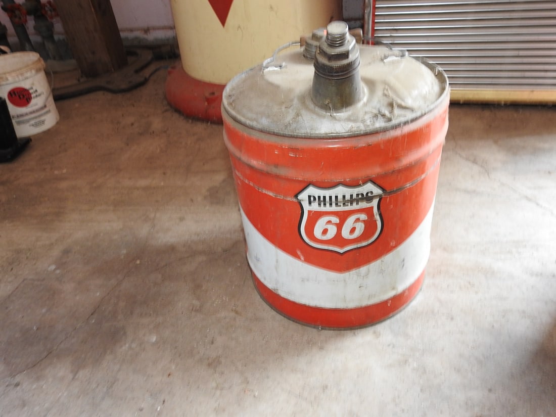 Vintage Phillips 66 Metal Oil Can: Vintage Phillips 66 metal oil can with red and white graphics, metal lid, and handled can form. Shows paint wear, scratches, dents, oxidation, staining, and age-related use wear. Approx. 17 x 12 x 12