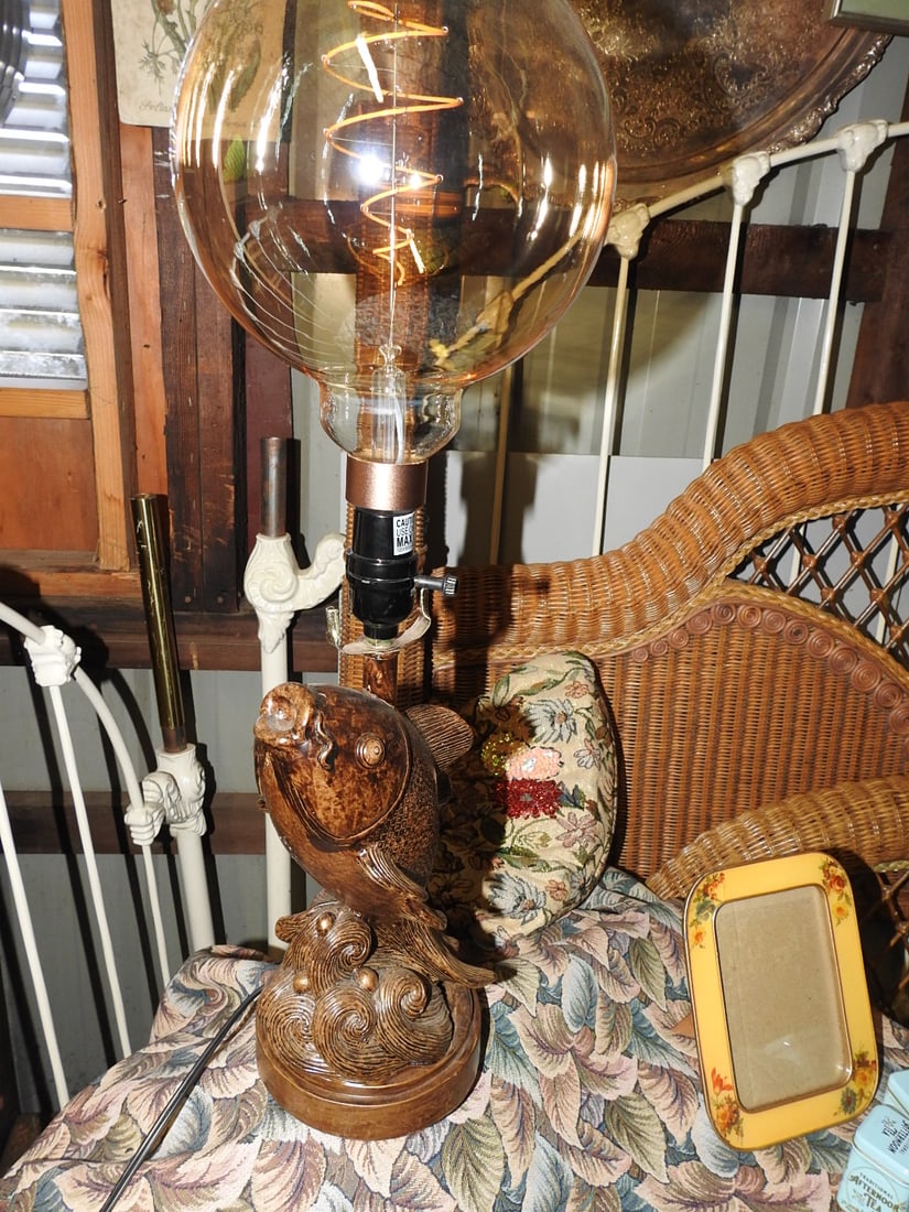 Leaping Fish Statement Lamp: Leaping fish statement lamp with bronze/cast metal-style fish base and large globe-style Edison bulb. Approx. 26 H x 7 W x 7 D in.