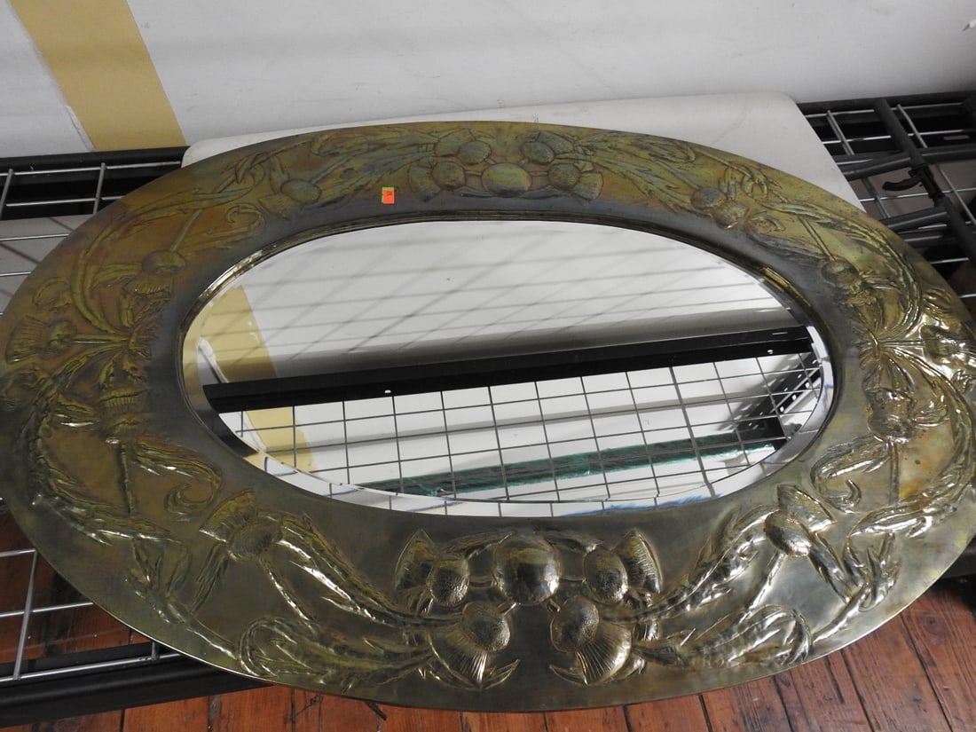 Antique Oval Pebbled Mirror with Embossed Brass Frame: Art Nouveau Copper Repousse Antique oval pebbled mirror with embossed brass frame featuring raised floral/leaf decoration and hanging chain on back. Approx. 1 x 36 x 24 in.