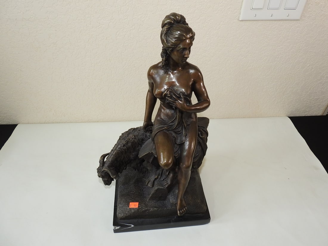 Bronze Amalthea Statue on Marble Base after Pierre Julien: Bronze figural statue after Pierre Julien depicting Amalthea seated on a rock holding ribbons tied to the horns of Jupiter's goat. Mounted on a black marble base. Approx. 17 x 8.75 x 7.75 in.
