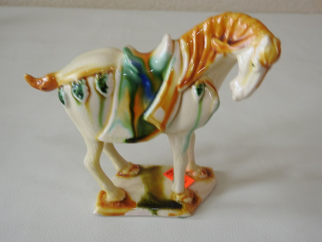 Majolica Style Off-White Tang Horse Figurine: Ceramic Majolica style Tang Dynasty horse figurine in off-white with yellow, blue, and green accents. Approx. 5 x 5 x 1.75 in.