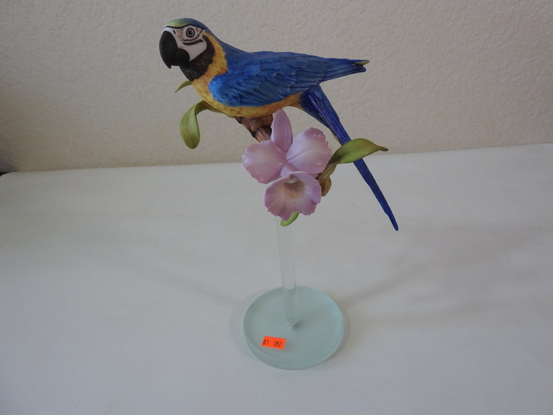 Vintage Porcelain Blue and Gold Macaw Figurine: Vintage porcelain blue and gold macaw bird figurine, made in China, with clear glass base. Approx. 11 x 7 x 4 in.