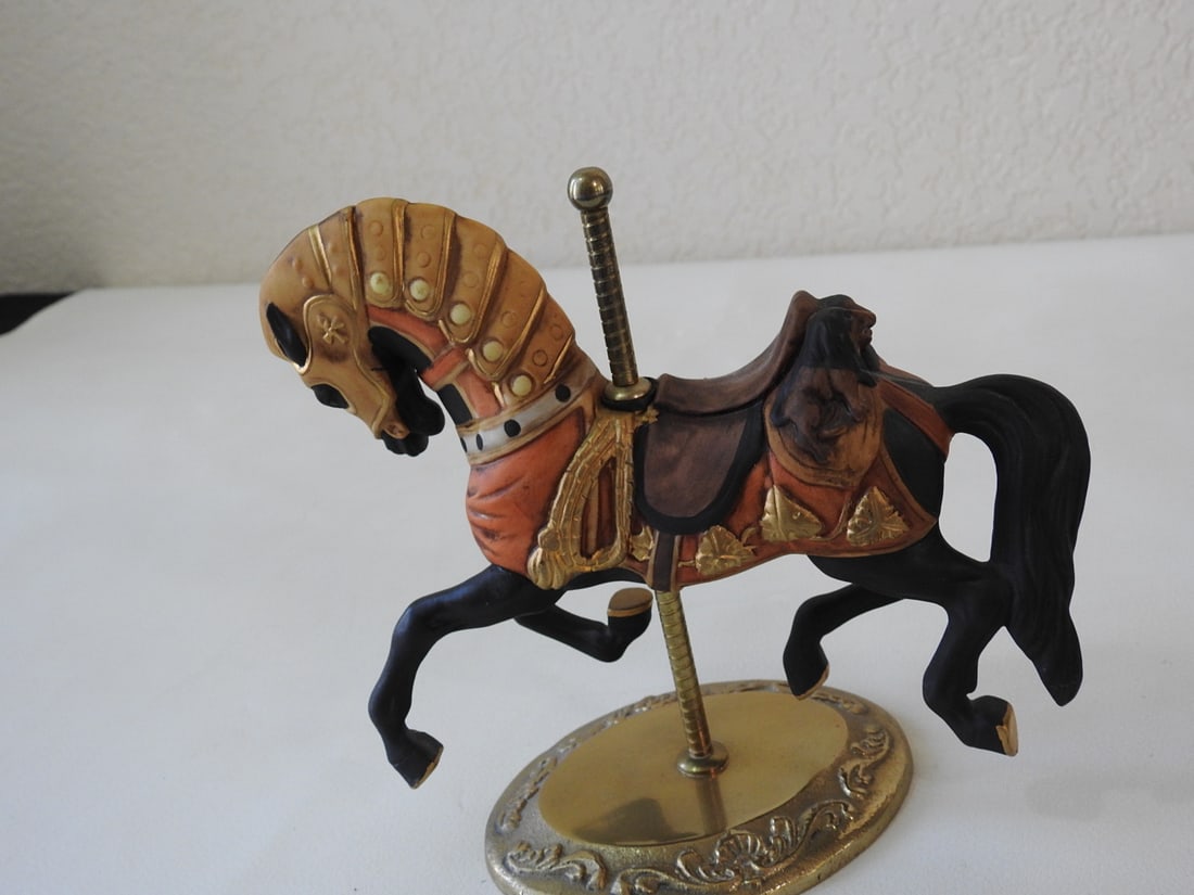 Black Porcelain Carousel Horse with Gold Accents: Porcelain standing carousel horse with black body, brass base, brass pole, and gold accents. Approx. 6.75 x 8 x 3.5 in.