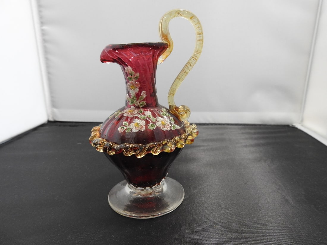 Victorian Style Cranberry Glass Vase: Victorian style hand-blown cranberry glass vase with apple ribbon girdle, handle, hand-painted detail, and glass stippling. Approx. 5.5 x 2.75 x 3 in.