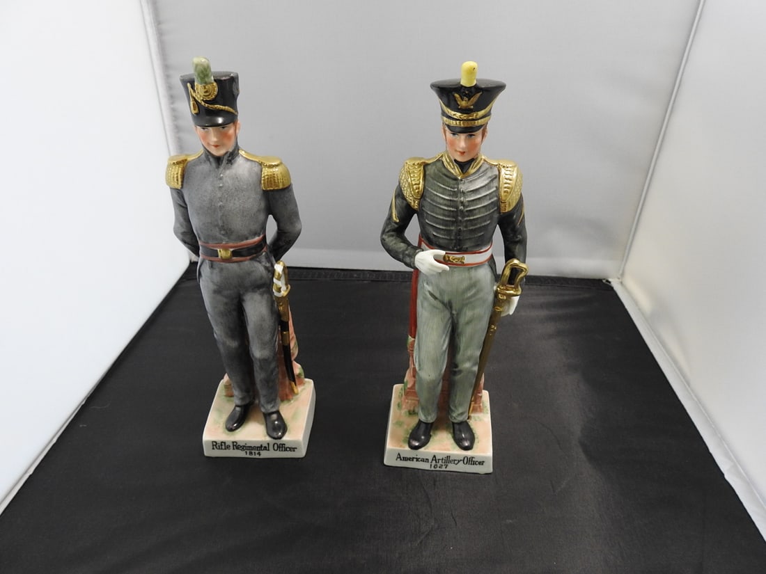 Porcelain Military Officer Figures, 1814 and 1827: Porcelain figures depicting 1814 Rifle Regiment officer and 1827 American Artillery officer, hand-painted with gold gilt in Regency period style, serial #7911. Approx. 9 x 2.5 x 4.5 in.