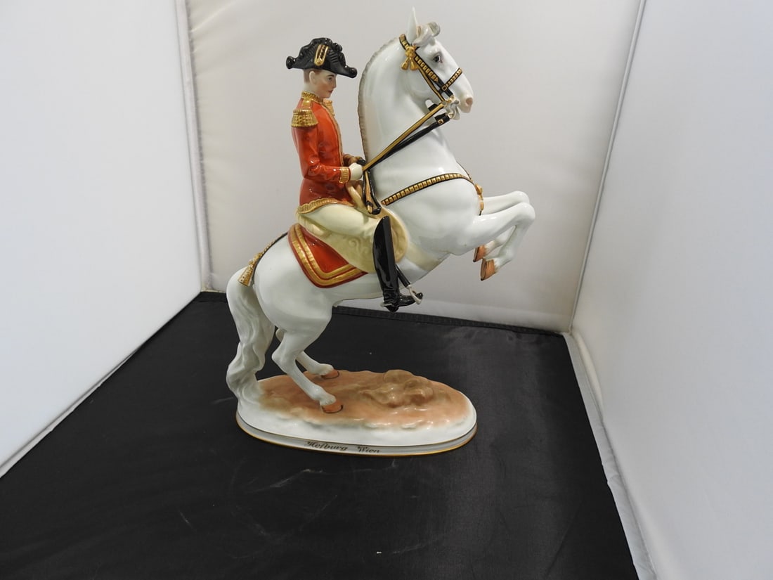 Hofburg Wien Lipizzaner Stallion and Rider Porcelain Figure: Hofburg Wien porcelain Lipizzaner stallion and rider figure with gold gilt accents. Sword has a break and repair as shown. Approx. 11.25 x 8 x 4 in.