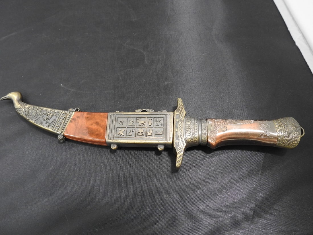 Egyptian Hieroglyphic Ceremonial Knife: Egyptian Hieroglyphic Ceremonial Knife. Stainless steel blade, cast metal coated in brass for the case, faux wood Approx. 9.5 x 3 x 1 in.