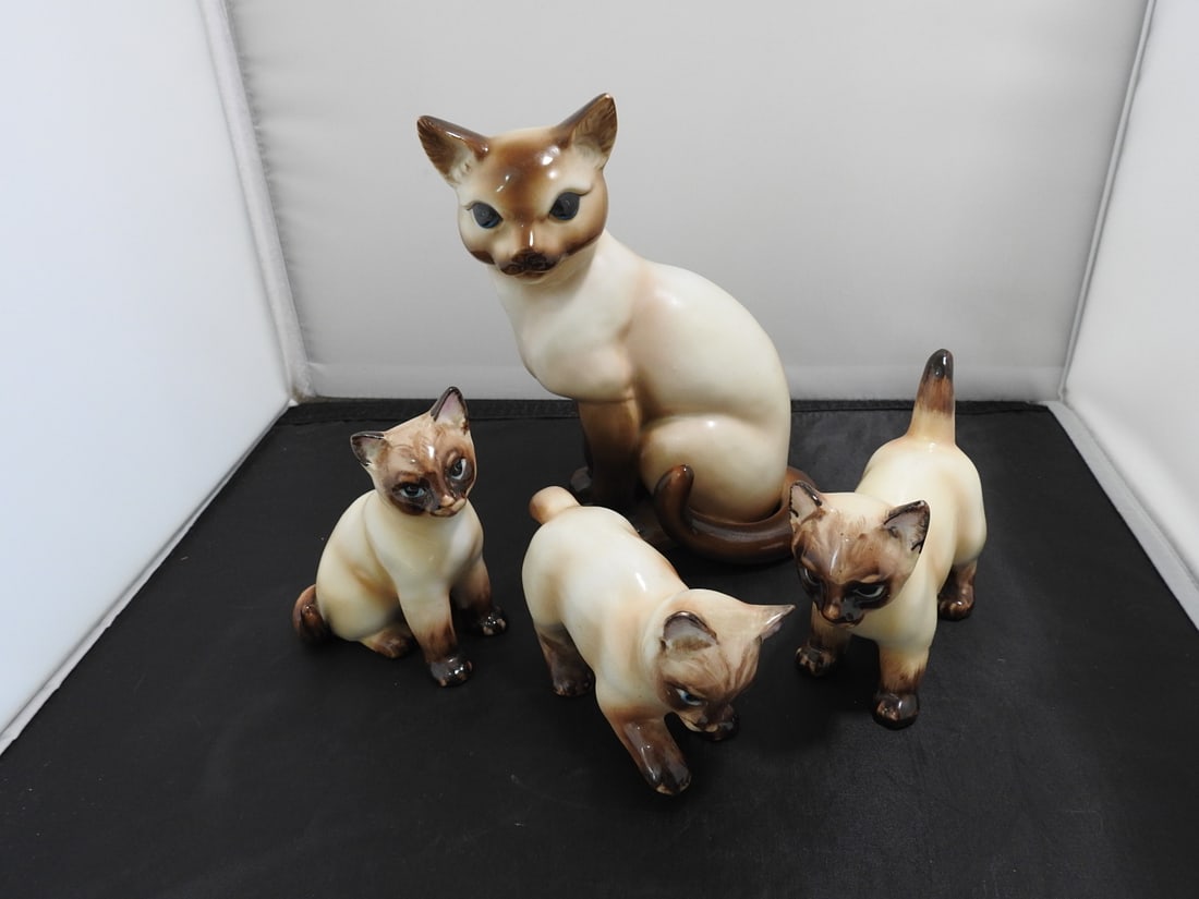 Set of Four Japanese Porcelain Siamese Cat Figures: Set of four porcelain Siamese cat figures including mother cat and three kittens. Made in Japan; kittens marked serial no. 2460. Baby cats are airbrushed and hand-painted; mother cat is airbrushed.