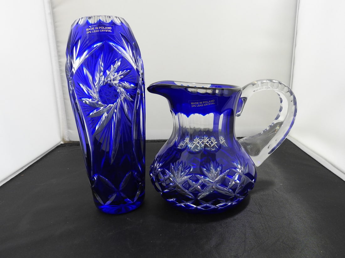 Pair of Cobalt Blue Cut Crystal Vase and Pitcher: Pair of cobalt blue cut lead crystal pieces including vase and pitcher with clear cut floral/star decoration. Made in Holland; genuine cut-away glass per notes. Approx. 7.5 x 6.5 x 7 in.