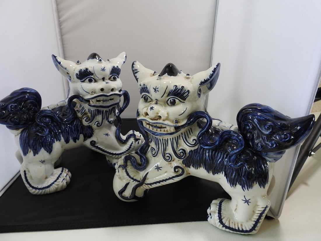 Vintage Blue and White Porcelain Foo Dogs Pair: Pair of vintage blue and white porcelain foo dog / guardian lion figures with cobalt painted decoration, raised details, and green felt to undersides. Measured as a set. Approx. 9.25 x 13 x 10 in.